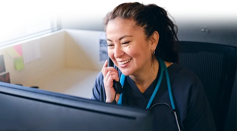Employee on phone with patient smiling next to a computer